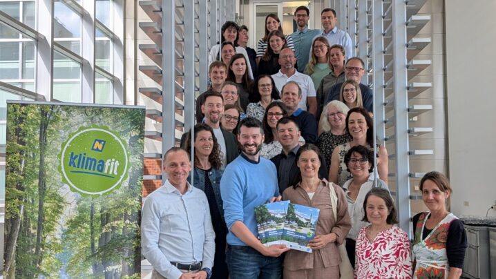 Gruppenfoto mit den NÖ KLAR! Managerinnen und -Managern im Landhaus St. Pölten. Klimafit-Roll Up auf der linken Seite. Die Personen stehen auf einer Treppe.