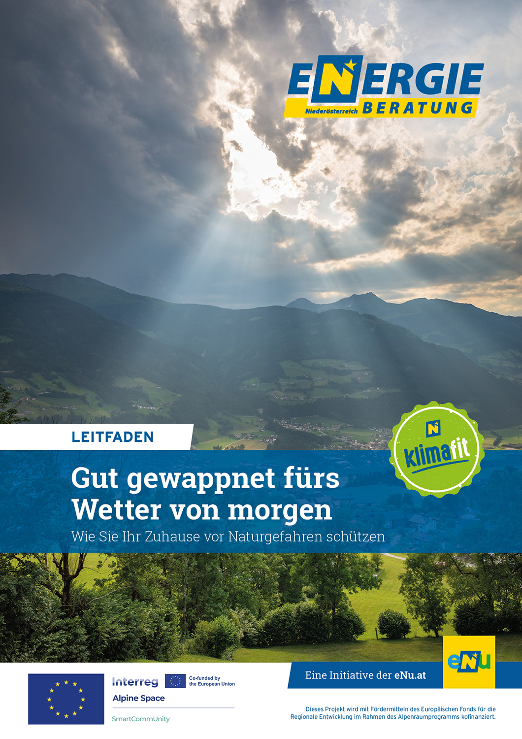 Sonne scheint durch Wolken auf Talfläche herab, im Hintergrund dunkle Berge, vorne etwas Grün