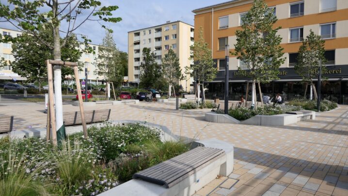 begrünte Beete mit Bäumen, Pflastersteine, neue Sitzgelegenheiten