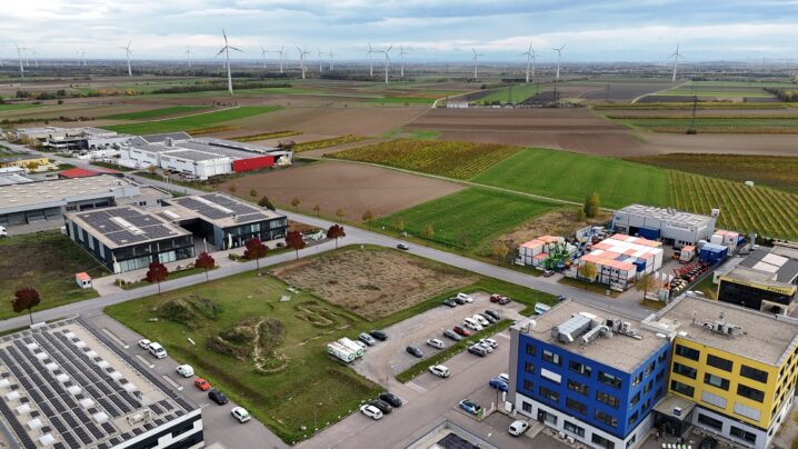 Aufnahme mit Drohne, im Vordergrund Gebäude des Gewerbegebietes, im Hintergrund Felder und Windenergieanlage.
